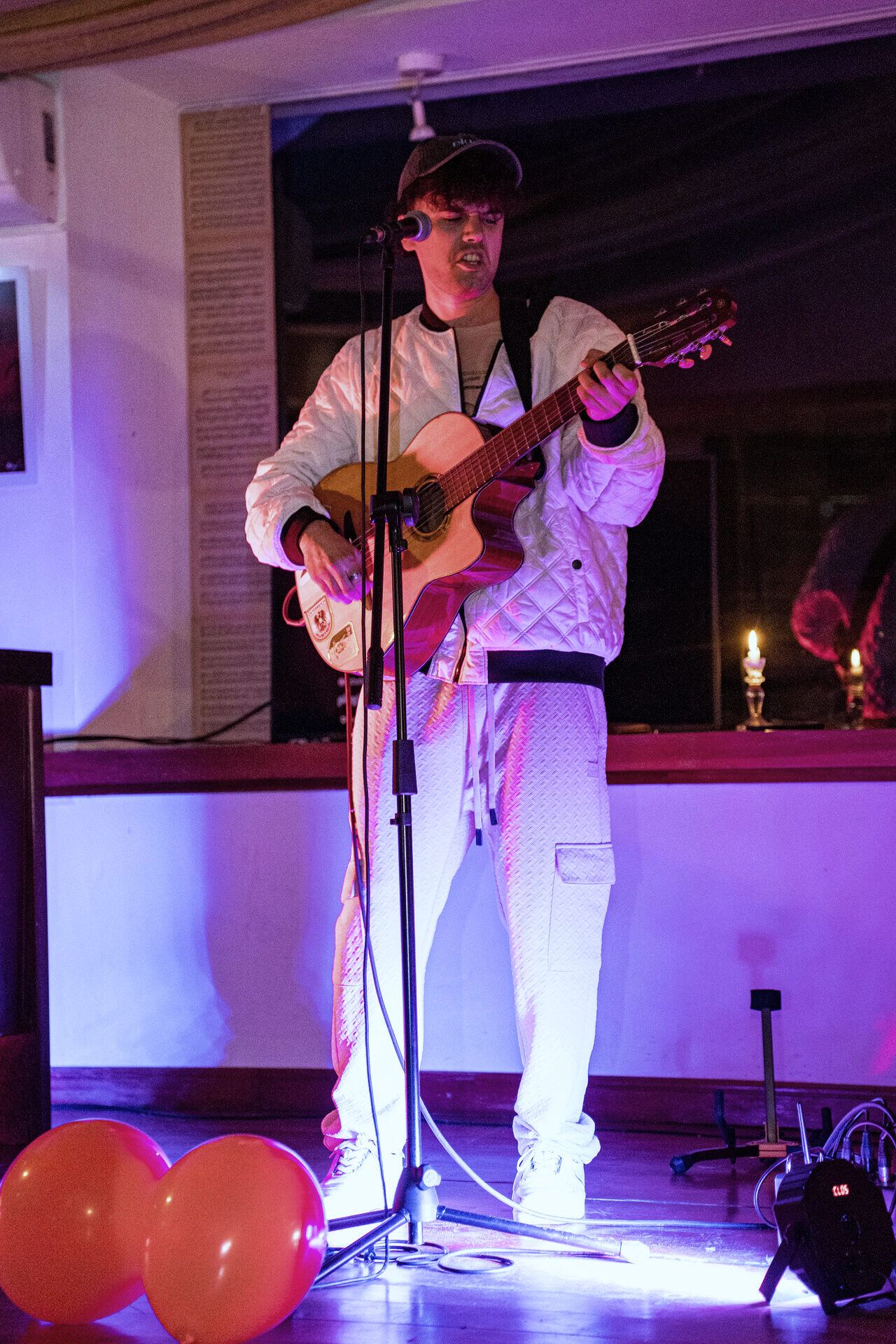 Guitarrista tocando en vivo bajo luces magenta y violeta.